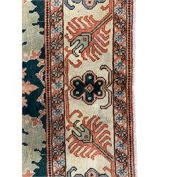 Persian emerald green ground rug, the field decorated with large stylised plant motifs, ivory ground border with repeating leaf motifs, the guards decorated with trailing branch and flowerhead motifs