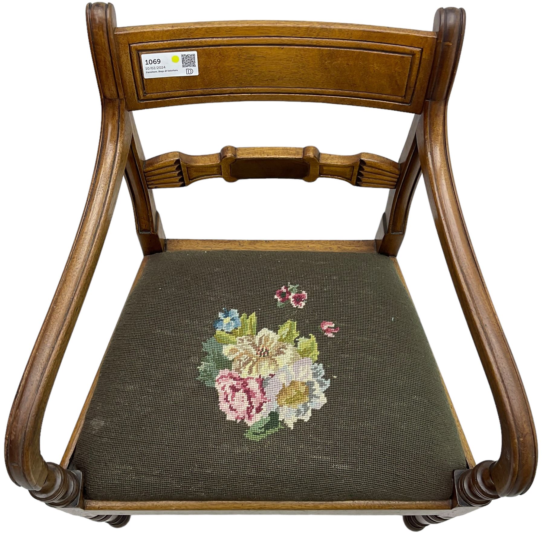 Regency mahogany elbow chair, carved shaped central back bar, over drop-in seat upholstered in floral needlework, raised on ring turned front supports