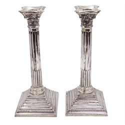 Pair of modern silver Corinthian column candlesticks, each with removable sconces with dart edging and embossed detailing, with personal engraving in a Semitic language, upon weighted stepped square bases, hallmarked Birmingham 1962, maker's marks HYC, H30.5cm