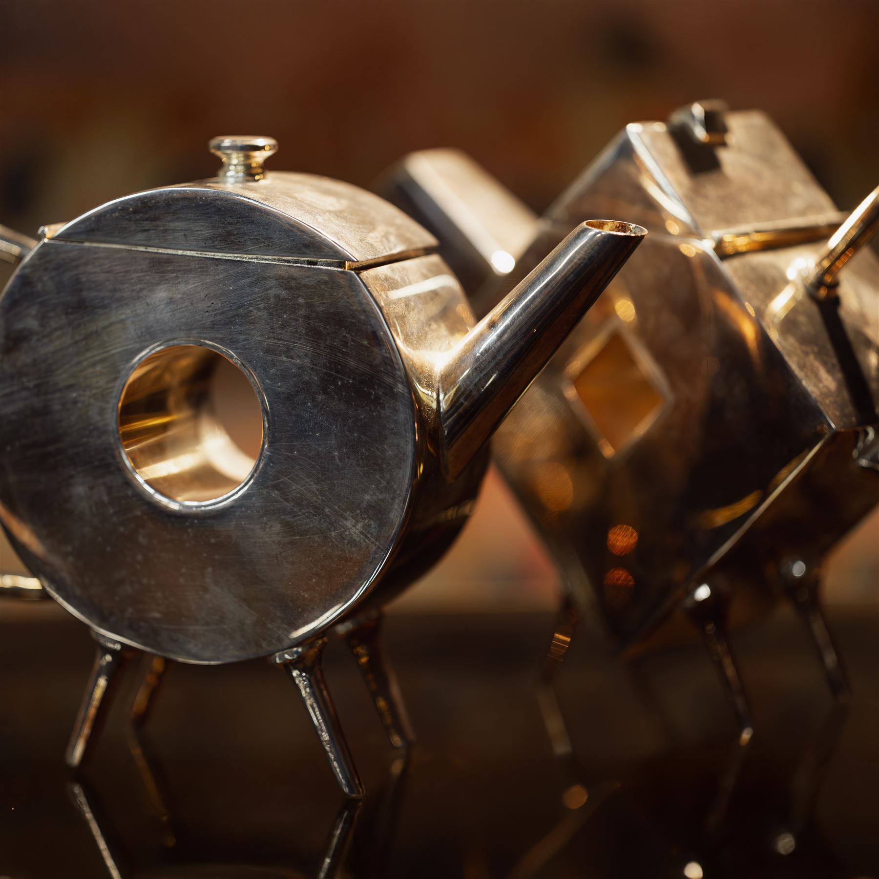 Manner of Christopher Dresser (1834-1904) - two art deco design silver plated teapots, of circular and square form with vacant centre, ebonised handles, each marked and with registration mark, max H18cm (2)