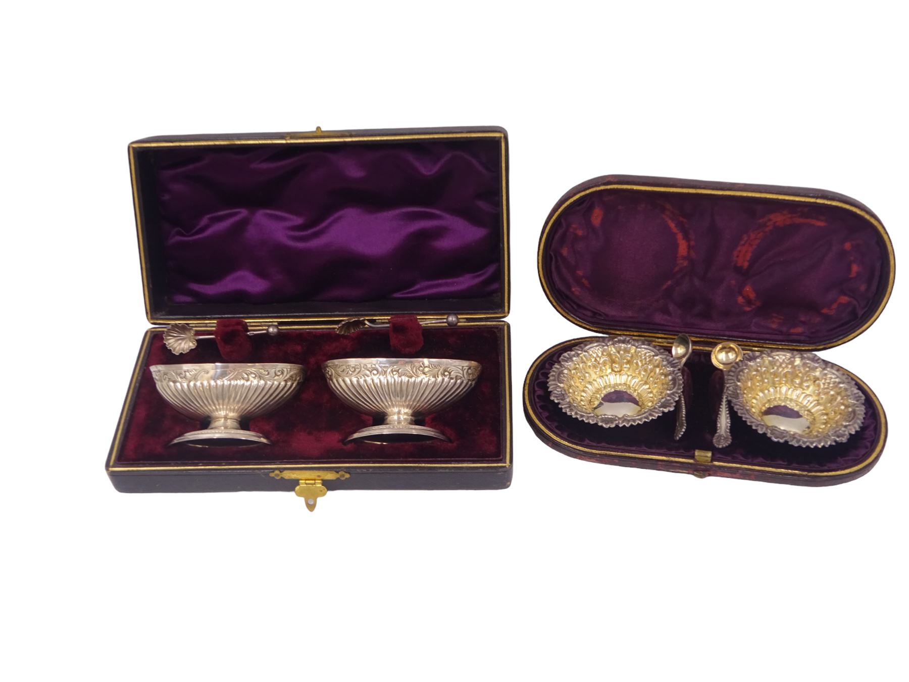 Pair of Victorian silver open salts, of part fluted navette form, with engraved foliate decoration, upon oval stepped foot, hallmarked W H Lyde, Birmingham 1896, H3.5cm, together with a pair of silver salt spoons, with leaf shaped bowls and ball finials, hallmarked Joseph Gloster, Birmingham 1897, together with a pair of Victorian silver open salts, of circular form, with shaped rim and embossed scroll and lattice decoration to the gilded bowl, together with pair of matching silver salt spoons, hallmarked Albert Sydenham, Birmingham 1899, both sets within tooled leather, velvet and silk lined fitted cases