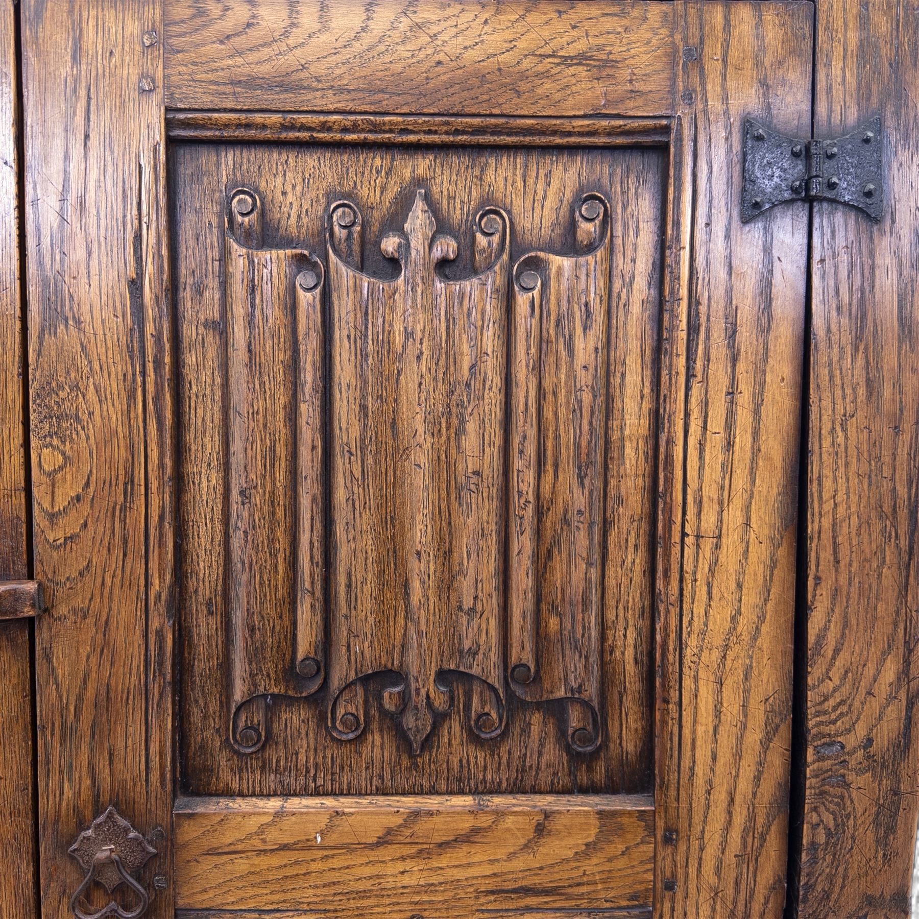 Mid 20th century oak double wardrobe, the rectangular top above twin panelled doors with carved linenfold decoration and wrought iron hinges, raised on block feet