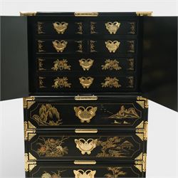 Japanese Shibayama style black lacquered curio chest, cupboard doors enclosing four short over two long fitted drawers, decorated in gilt with birds, flowers and landscape scenes, raised on gilt mounted bracket feet