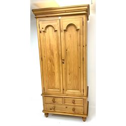 Classical pine double wardrobe, two doors enclosing hanging rail above two short and one long drawer, typically supports 