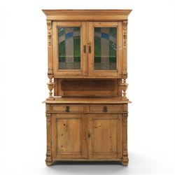 Late 19th century French pine dresser with stained glass upper section, the upper section with projecting cornice with fluted and scrolled details, enclosing a shelved interior, supported on turned front uprights, the lower section with frieze drawers and cupboard doors, raised on bun feet