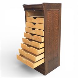 Early 20th century oak tambour front fitted cabinet, rectangular top with rounded corners over a roll tambour front enclosing a fitted interior of multiple shallow drawers with cut-out pulls, the sides with rounded uprights, on a stepped plinth base