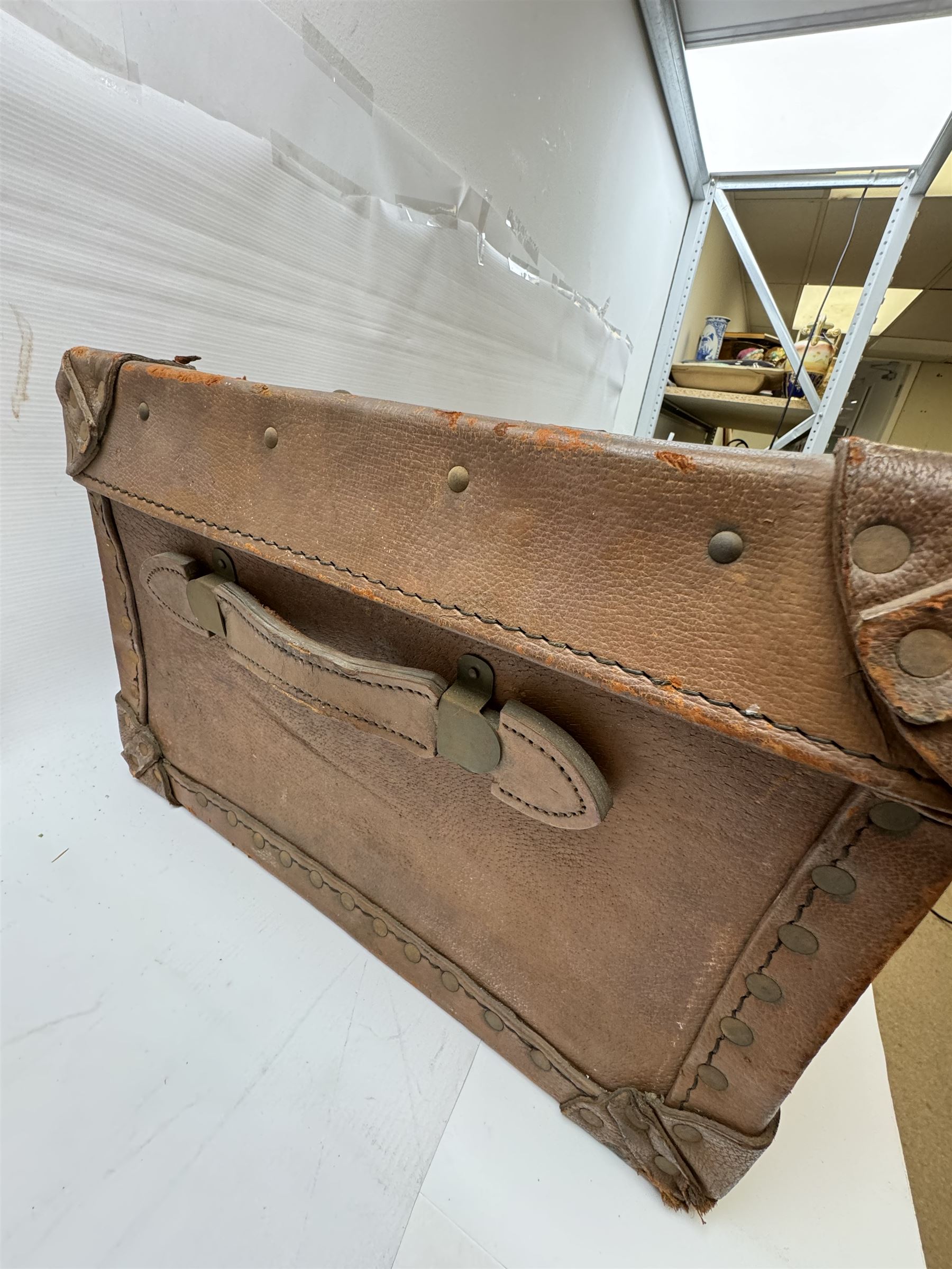 Early 20th century leather trunk, with brass fixtures, leather straps and buckle fastenings, embossed to the top with initials GG, H28cm, W76cm