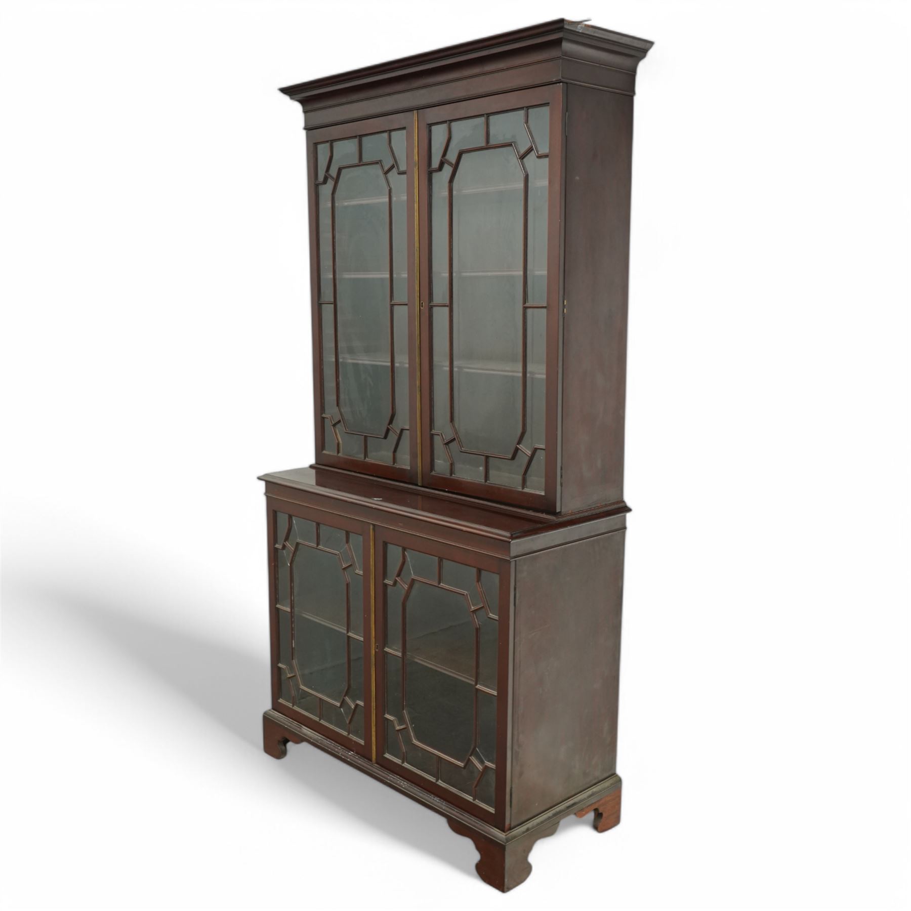Early 20th century Chippendale design mahogany bookcase, projecting moulded cornice over four astragal glazed doors, the interior fitted with adjustable shelves, on bracket feet 