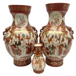 Pair of Japanese Meiji period Kutani vases, of twin handled baluster form finely painted with dense panels of figures and flowers upon foliate gilt decorated iron red ground, both with dragon mask ring handles, with red script mark beneath, together with a further matching smaller example, tallest H35cm