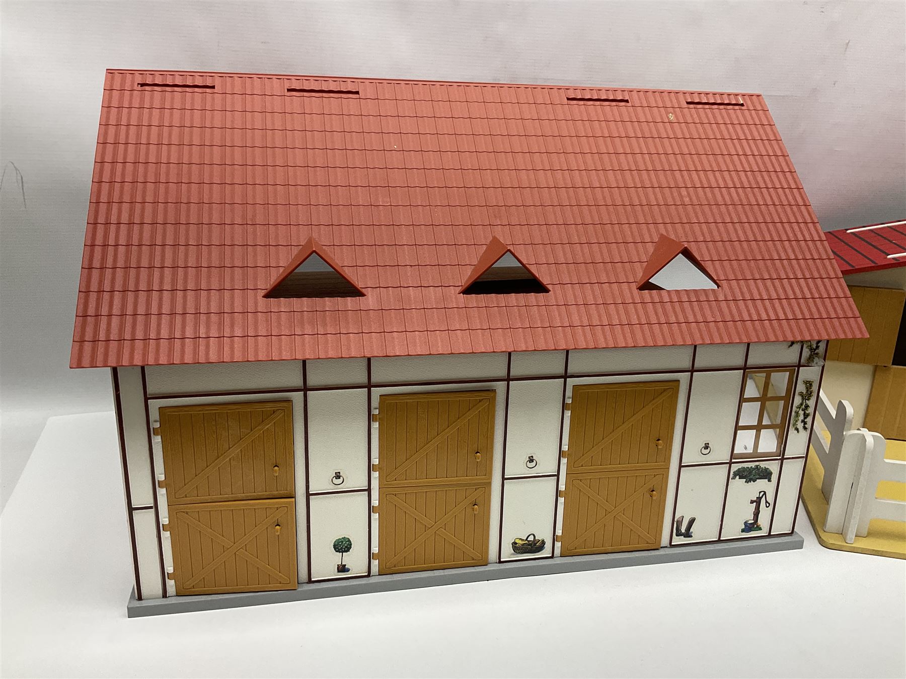 Sectional wooden horse stables playset by Julip with two stalls and tack room under a pitched roof, base 59 x 47cm; and another sectional plastic stables playset by Schleich with three stalls under an open pitched roof, base 56 x 36cm (2)