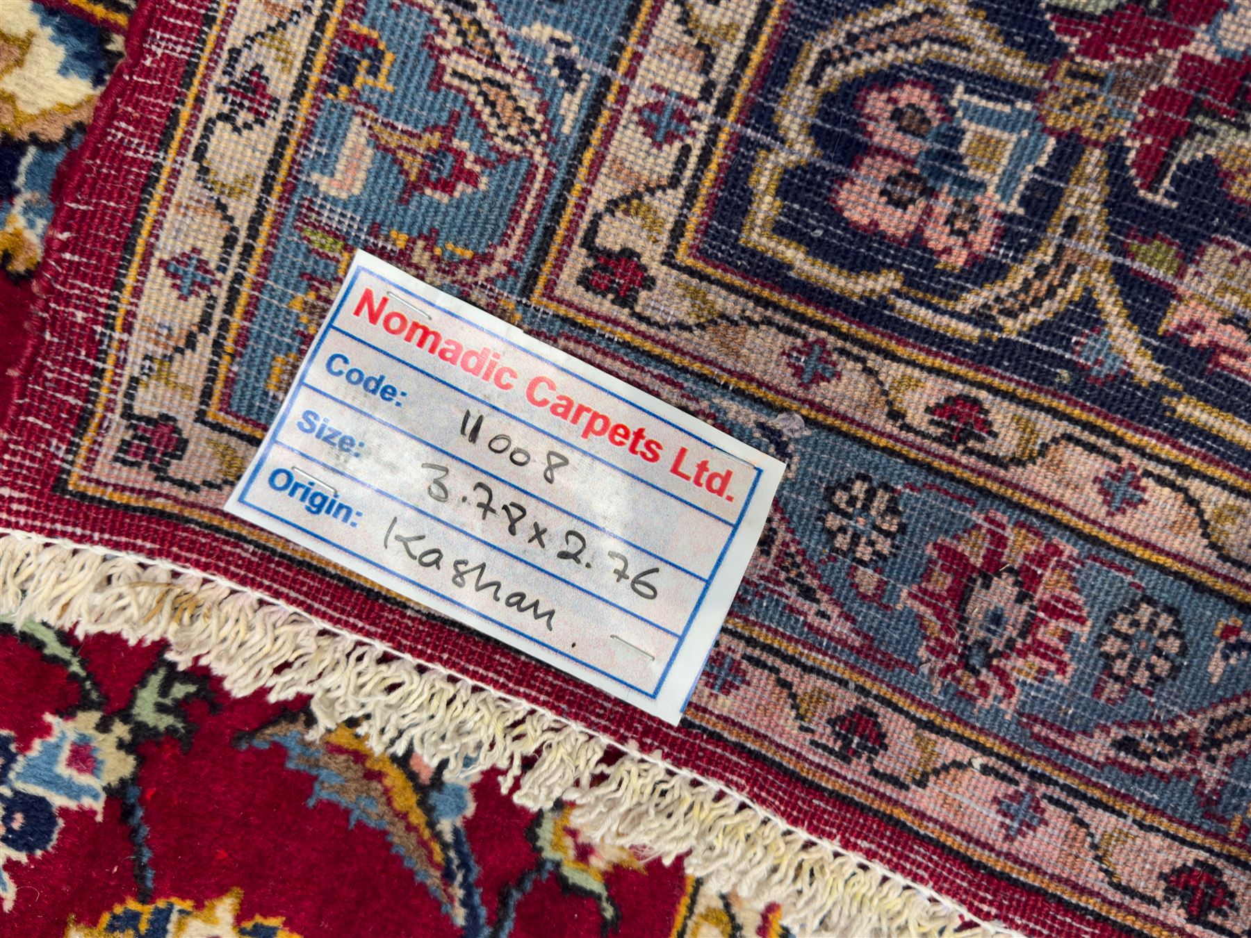 Northeastern Persian Meshed hand-knotted carpet, madder red field with an all-over design of scrolling vines, palmettes, and rosettes, within a dark blue border of palmettes and arabesques 