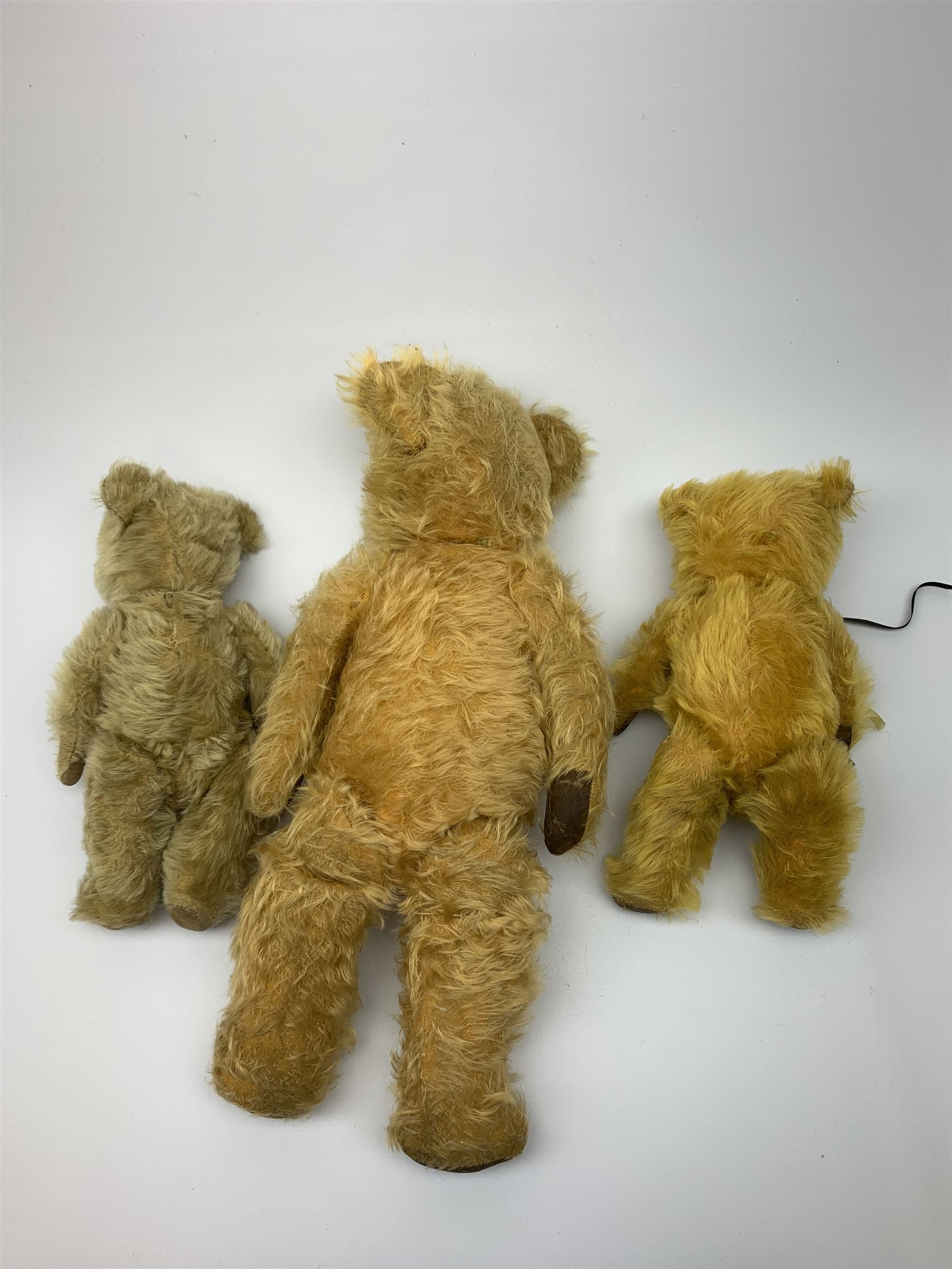 Three English teddy bears c1930s-50s comprising Chiltern wood wool filled Hugmee flat faced bear with swivel jointed head, vertically stitched nose and mouth and jointed limbs with rexine paw pads H12