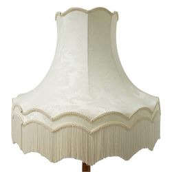 20th century walnut standard lamp, flared and faceted column over circular stepped base with shaped feet, with later scalloped cream fabric shade and fringe trim