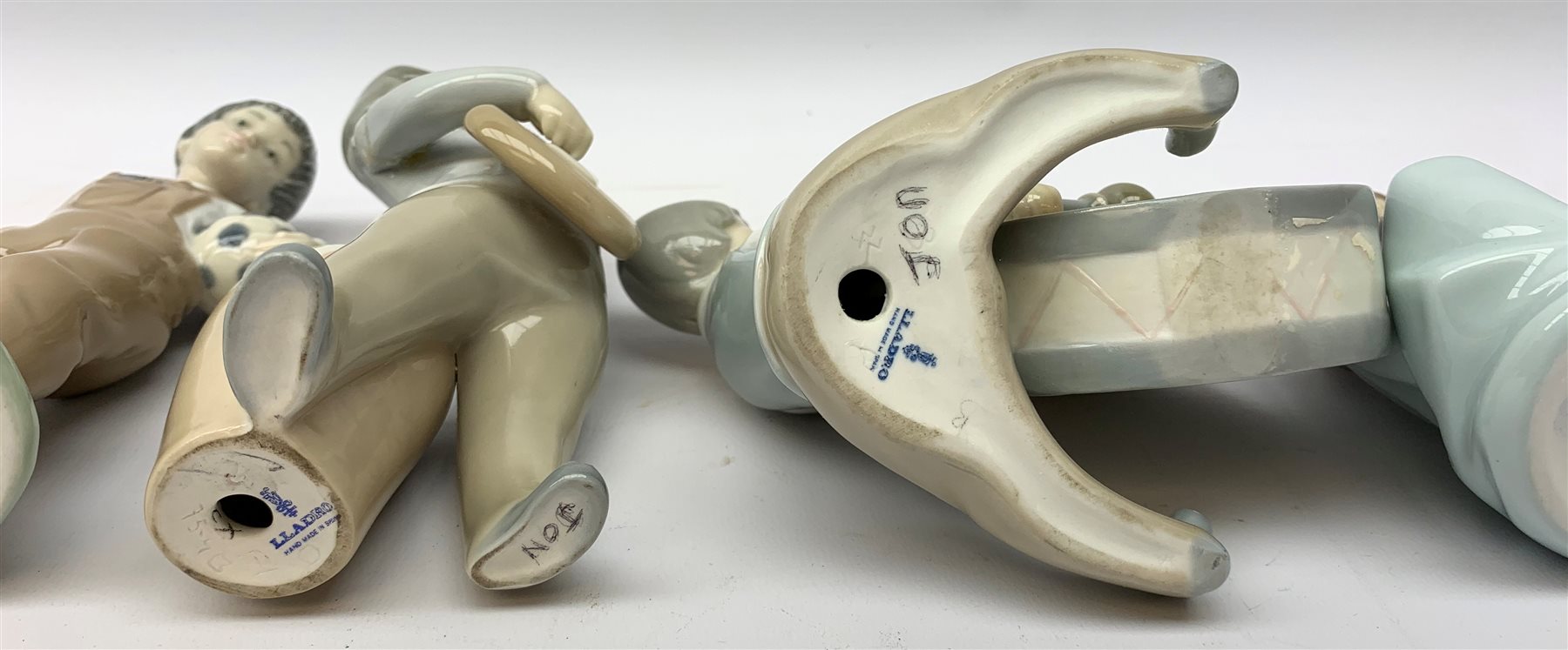  A group of Lladro and Nao figurines, comprising a trio modelled as boys playing instruments, boy with dog, boy with football, girl with puppy and kitten and a goose, (two a/f), all with printed mark beneath.   