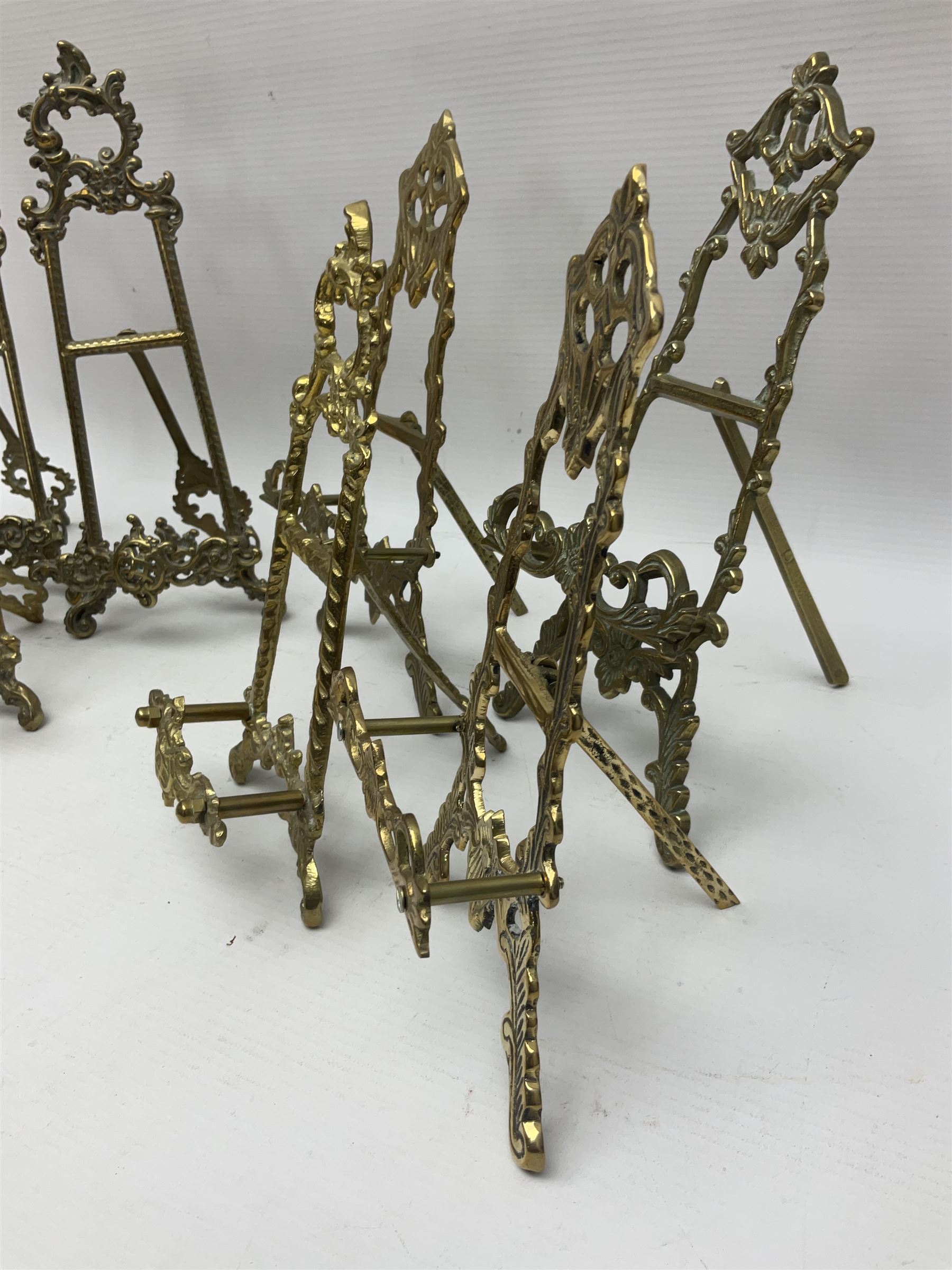 Nine ornate cast brass easel stands of various sizes, H24cm