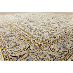 Central Persian Kashan hand-knotted rug, ivory field intricately decorated with an all-over design of scrolling vines, palmettes, and stylized lotus motifs in shades of soft blue, pale gold, and indigo within floral borders