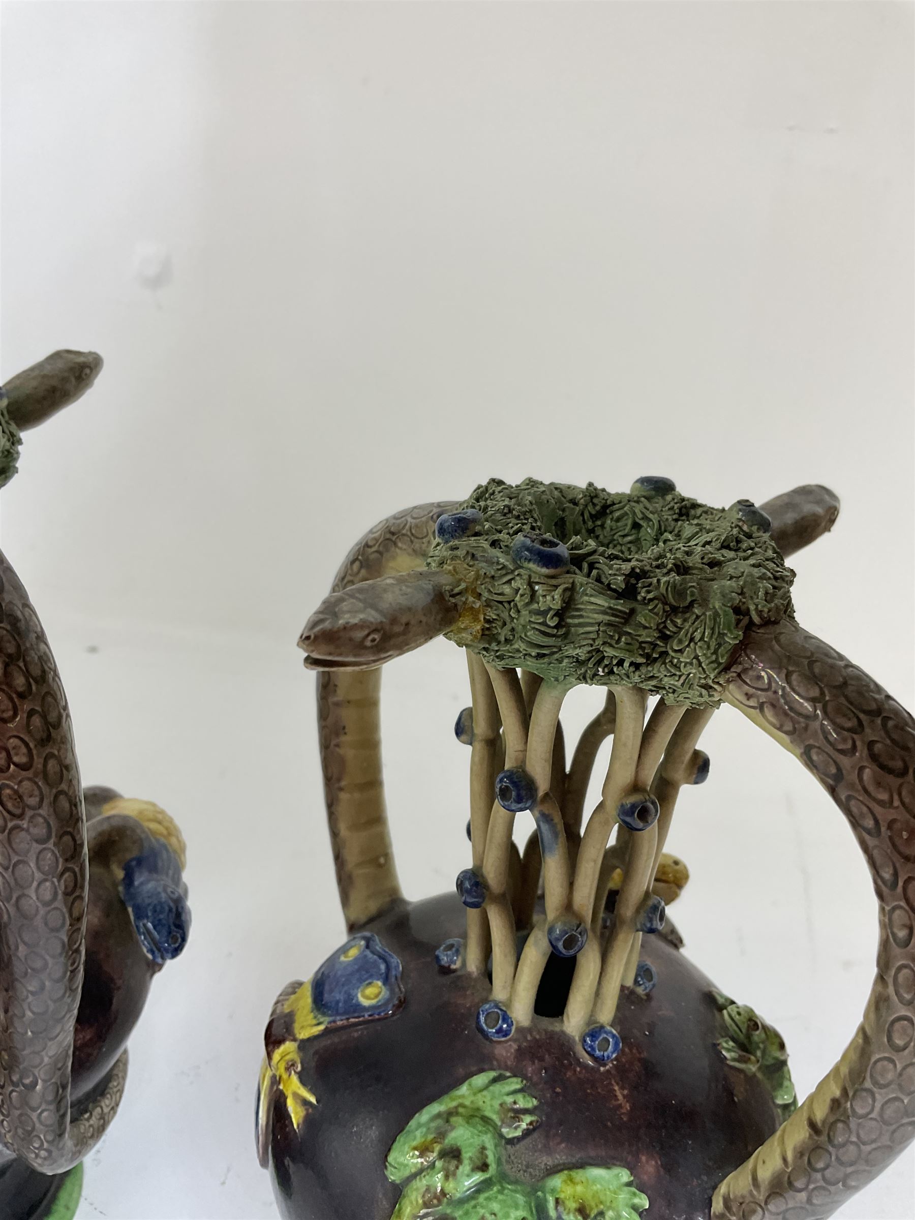Pair of 19th century Portuguese Palissy style Majolica puzzle jugs, attributed to Manuel Mafra, with mossy rim and pierced lattice neck, twin handles in the form of snakes and the body decorated with frogs, lizards, and moths on a mottled brown glazed ground, unmarked, H20cm