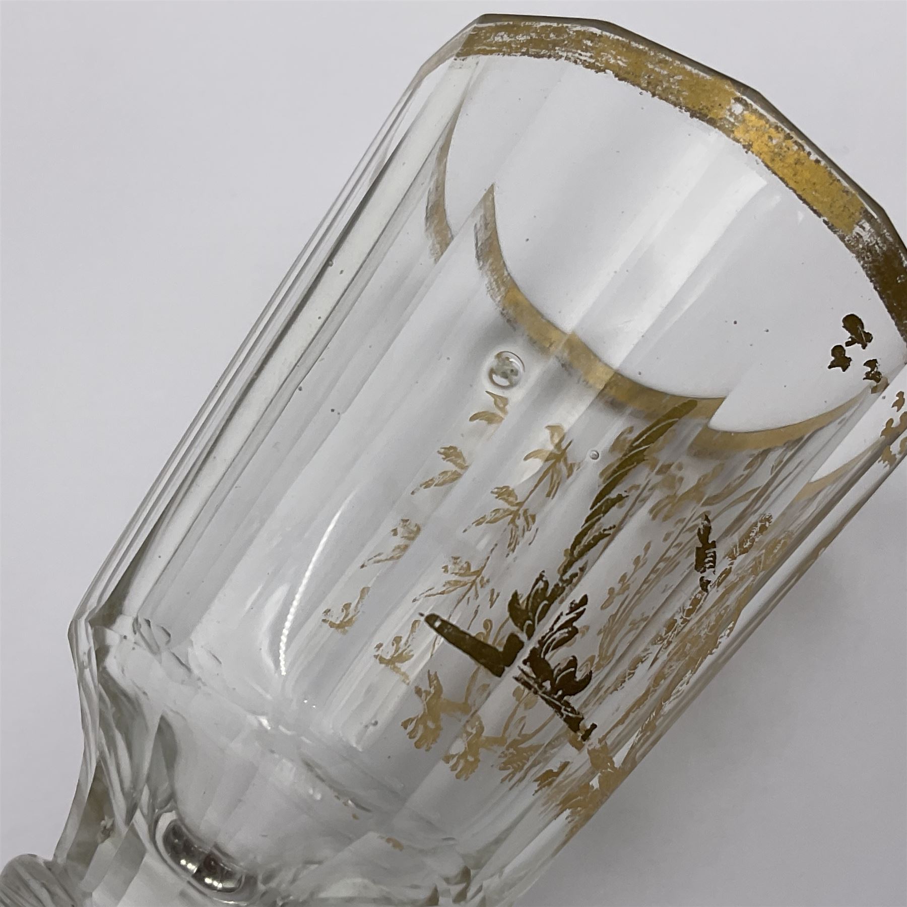 Three 18th century wine glasses comprising a plain stemmed glass with bell shaped bowl and conical folded foot H16cm, another plain stemmed glass with ogee bowl and folded foot and a Continental glass with gilt faceted bowl, decorated with male figure within a landscape, on a clear Silesian seven sided cut stem (3)