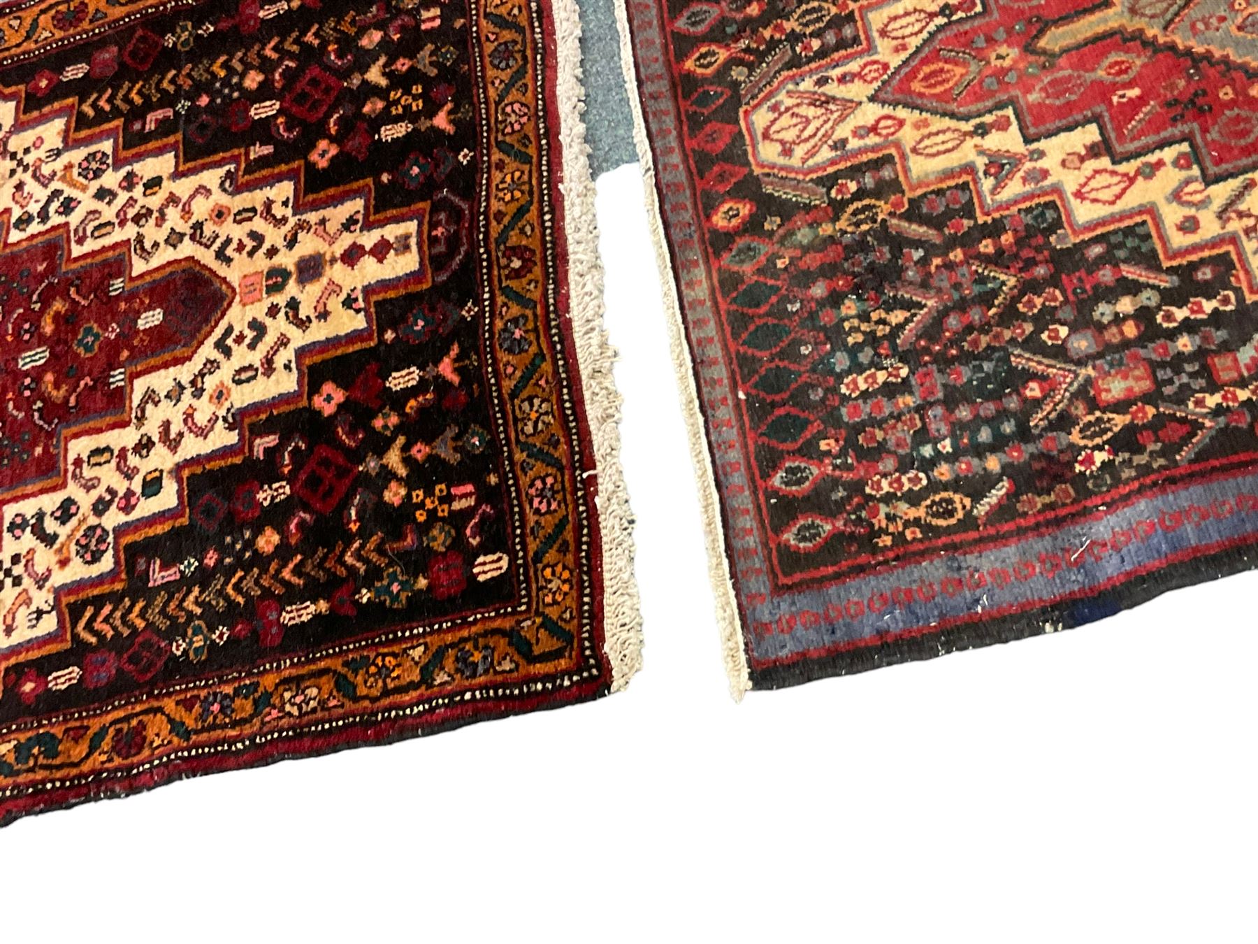Small Hamadan dark indigo ground rug, central ivory and maroon lozenge with geometric decoration, guarded border with repeating stylised plant motifs, together with three others (4)