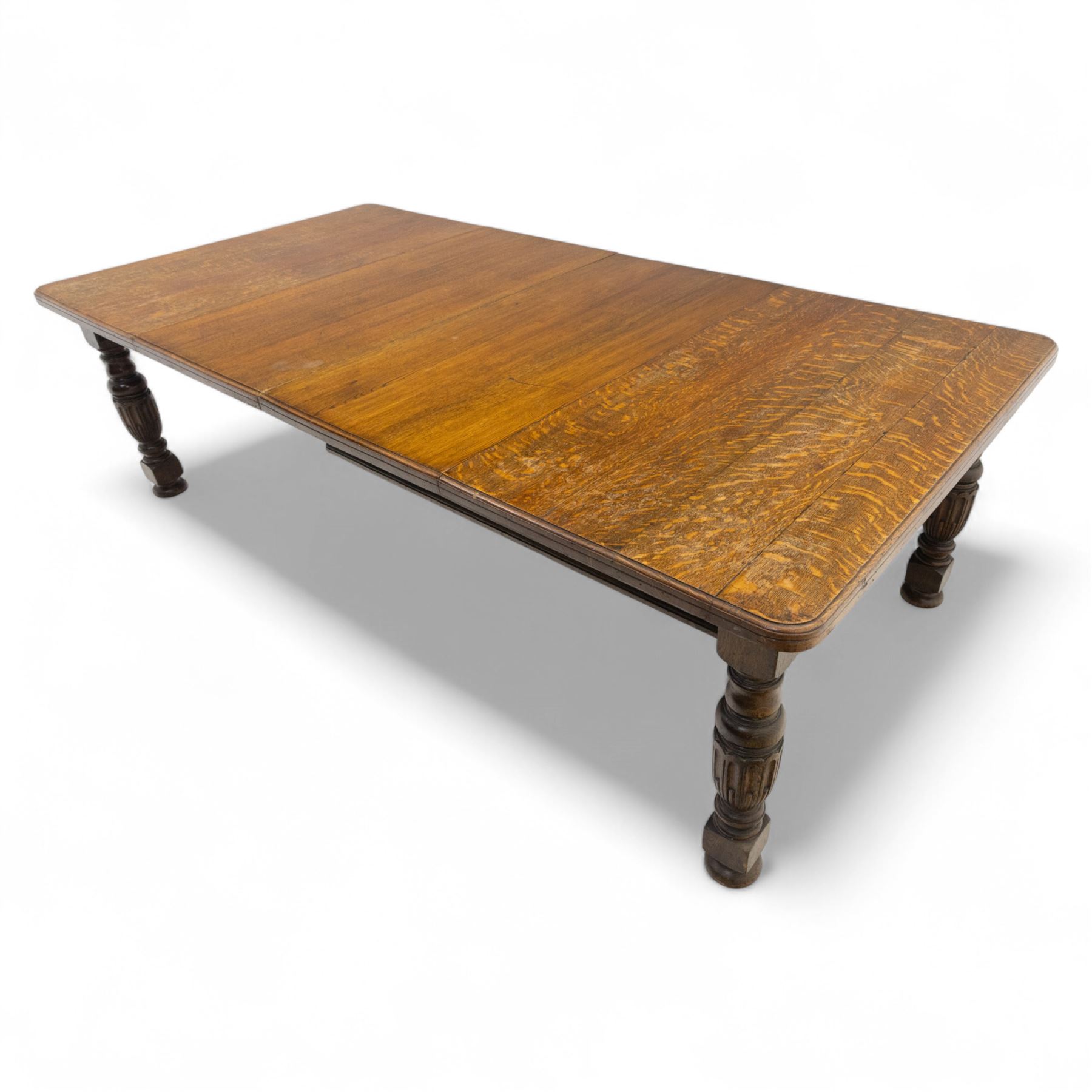 Victorian oak extending dining table, rectangular moulded top with figured grain pattern and wind-out action operated by removable crank handle, complete with additional leaves, raised on four boldly turned and reeded baluster supports terminating in squat bun feet (Extends to 238cm)
