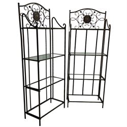 Pair of wrought metal conservatory plant stands, raised back with scrolling design, each fitted with three glass shelves