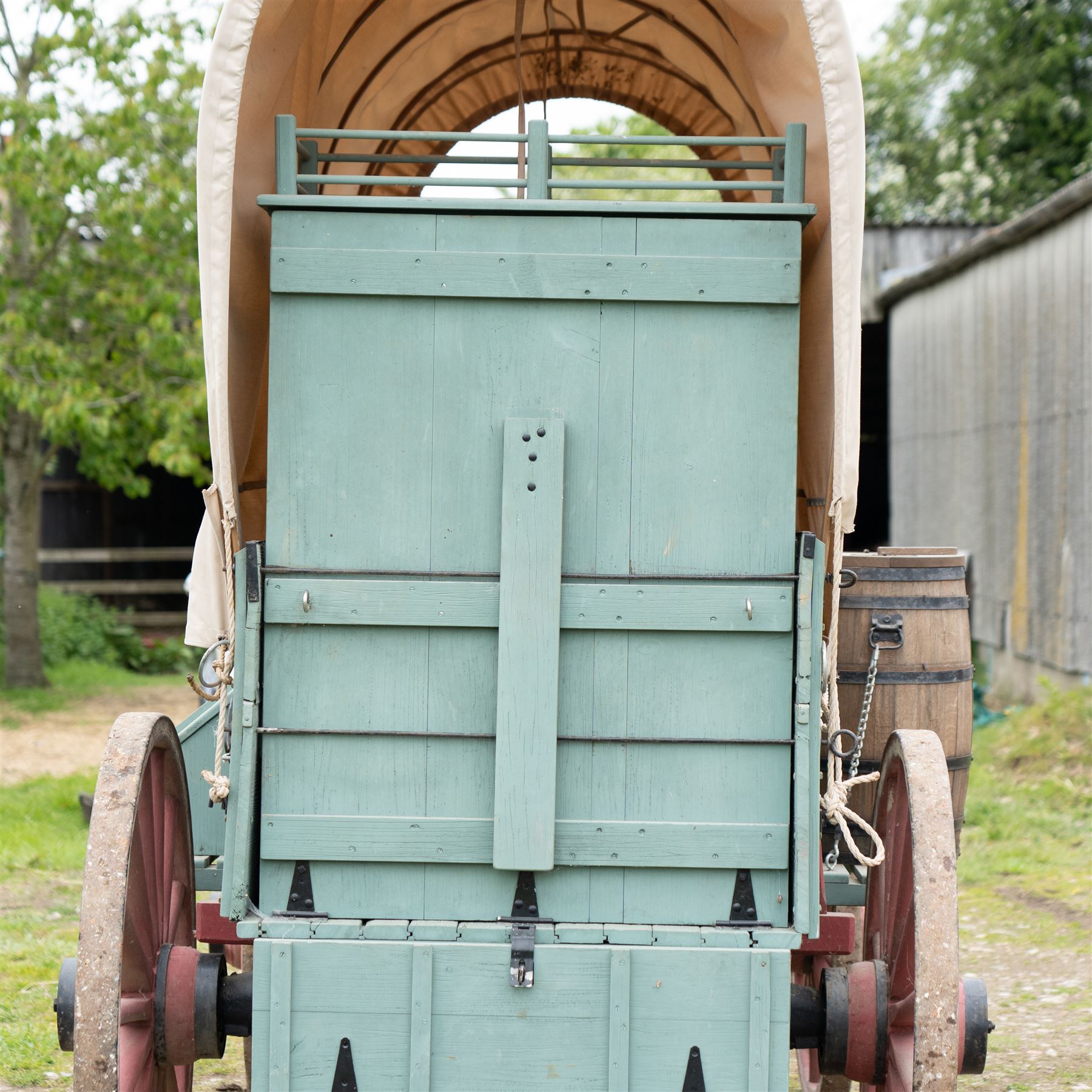 Western Covered Chuck Wagon

A large four wheeled covered wagon of timber construction, painted pale green with red painted wooden spoked wheels and a cream canvas tilt over an arched frame. The wagon has a traditional box body with covered rear compartment, front driving position, underbody turntable steering and iron fittings throughout. Fitted with external equipment details including a side mounted barrel, lidded storage chest, rope tie downs, horseshoe fittings and rear storage box.

Features

• Pale green painted timber body
• Cream canvas tilt over arched frame
• Covered rear compartment
• Front driving position
• Side mounted barrel
• External lidded storage chest
• Rear storage box
• Wooden spoked wheels
• Iron tyres
• Underbody turntable steering
• Rope tie downs
• Horseshoe fittings
• Iron hardware and brackets
• Brass restoration plaque to rear

Dimensions:
Overall length: 335 cm
Width: 170 cm
Height: 275 cm

Wheel Diameters:
Front wheels: 92 cm
Rear wheels: 112 cm

Seating:
Driver: 1
Passenger: Rear covered compartment