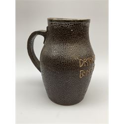 A Doulton Lambeth stoneware jug, with silver mounted collar, hallmarks rubbed, maker's mark probably Cornelius Desormeaux Saunders & James Francis Hollings (Frank) Shepherd, the leather effect body titled 'Drinke Faire Don't Sware', with impressed marks beneath including 'Manufactured for Sidney W Allen 39 White Rock Hastings', H18.5cm. 