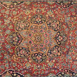 Persian Sarouk rug, richly decorated with an elaborate central medallion of palmettes and stylized floral motifs in indigo, ivory, and pastel tones on madder red ground, framed by spandrels, with a broad border of flowering palmettes and serrated leaves between a narrow floral guard border, fringe removed 