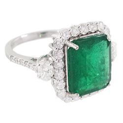 18ct white gold emerald and round brilliant cut diamond cluster ring, with two oval cut diamonds set either side and diamond set shoulders, stamped, emerald approx 4.30 carat,. total diamond weight approx 1.05 carat