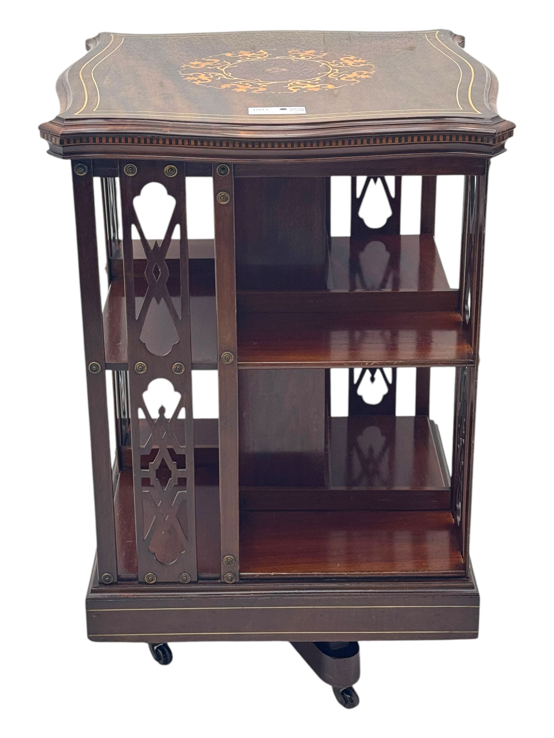 Edwardian inlaid mahogany revolving bookcase, shaped square moulded top with central motif and satinwood band, two tiers with pierced vertical splats, on swivel action base with ceramic castors