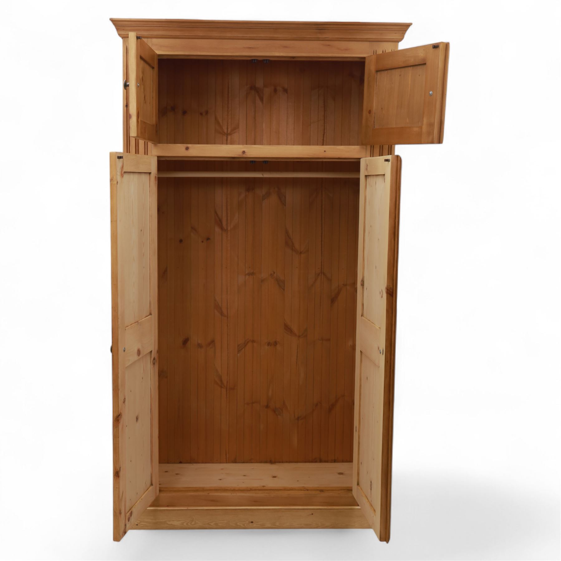 Modern stripped pine double wardrobe, with stepped cornice over upper cupboard doors and two full-height fielded panel doors, fluted stile detailing, ebonised knob handles, and plinth base