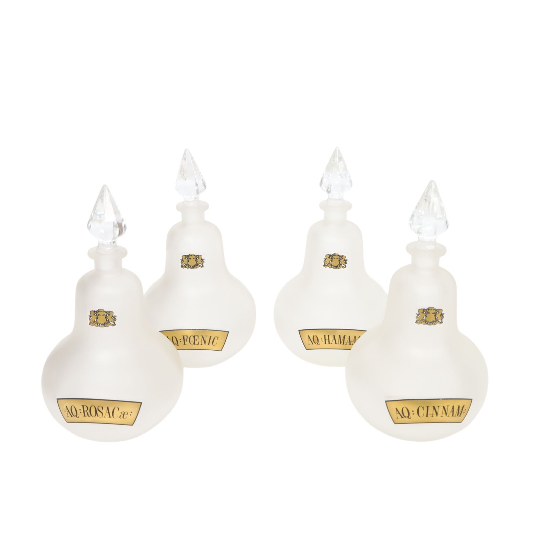 Set of four 20th century Royal Pharmaceutical Society white frosted glass bottles, of bellied form with clear cut glass spire stopper, each body bearing gilt label in Latin: AQ:CINNAM:, AQ:FOENIC:, AQ:HAMAM:, and AQ:ROSACae:, and gilt Royal Pharmaceutical Society crest to neck, H25cm

Provenance: From the collection of the family of Peter Green, a practising pharmacist whose career spanned the mid to late 20th century. During his professional life he managed pharmacies in Yeovil, Somerset, and later Selles Chemist in Filey, North Yorkshire, before purchasing and running his own business, Peter Green Pharmacy, located in the Market Place, Malton. The bottles were displayed as part of the traditional shop fittings in both the Filey and Malton pharmacies and were retained as part of his collection.
