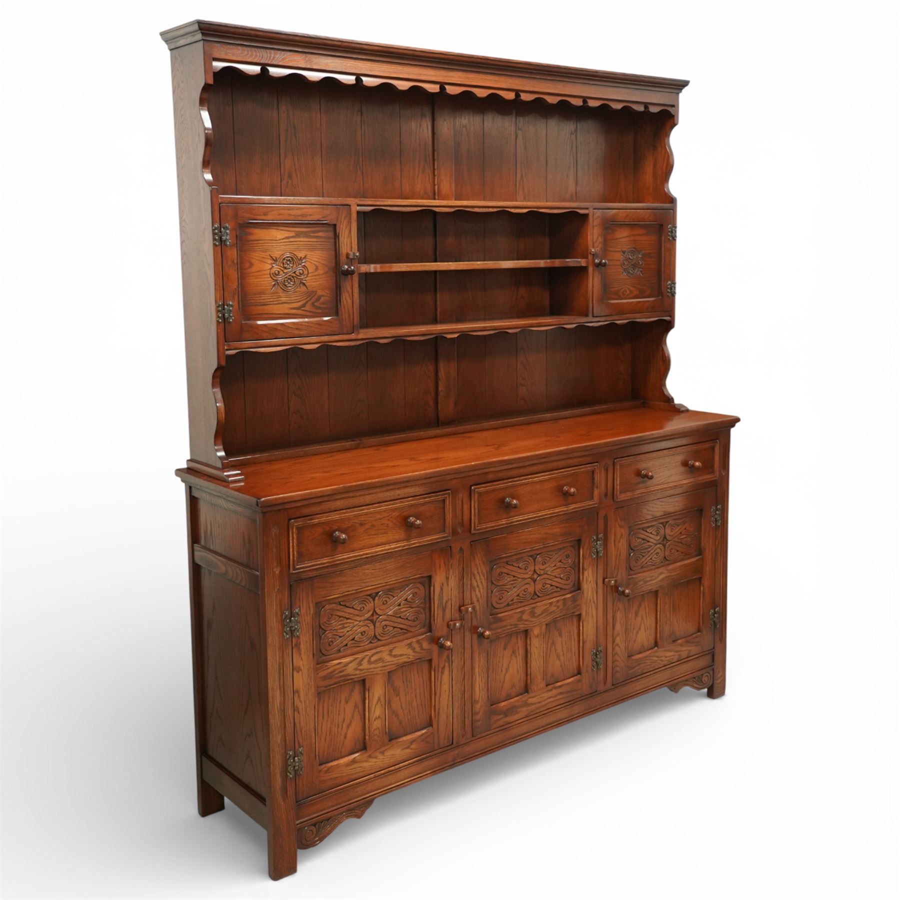 20th century oak dresser, moulded cornice above open plate rack with shaped frieze, flanked by two cupboard doors enclosing shelving, the base fitted with three drawers over three fielded panel cupboard doors, raised on bracket feet