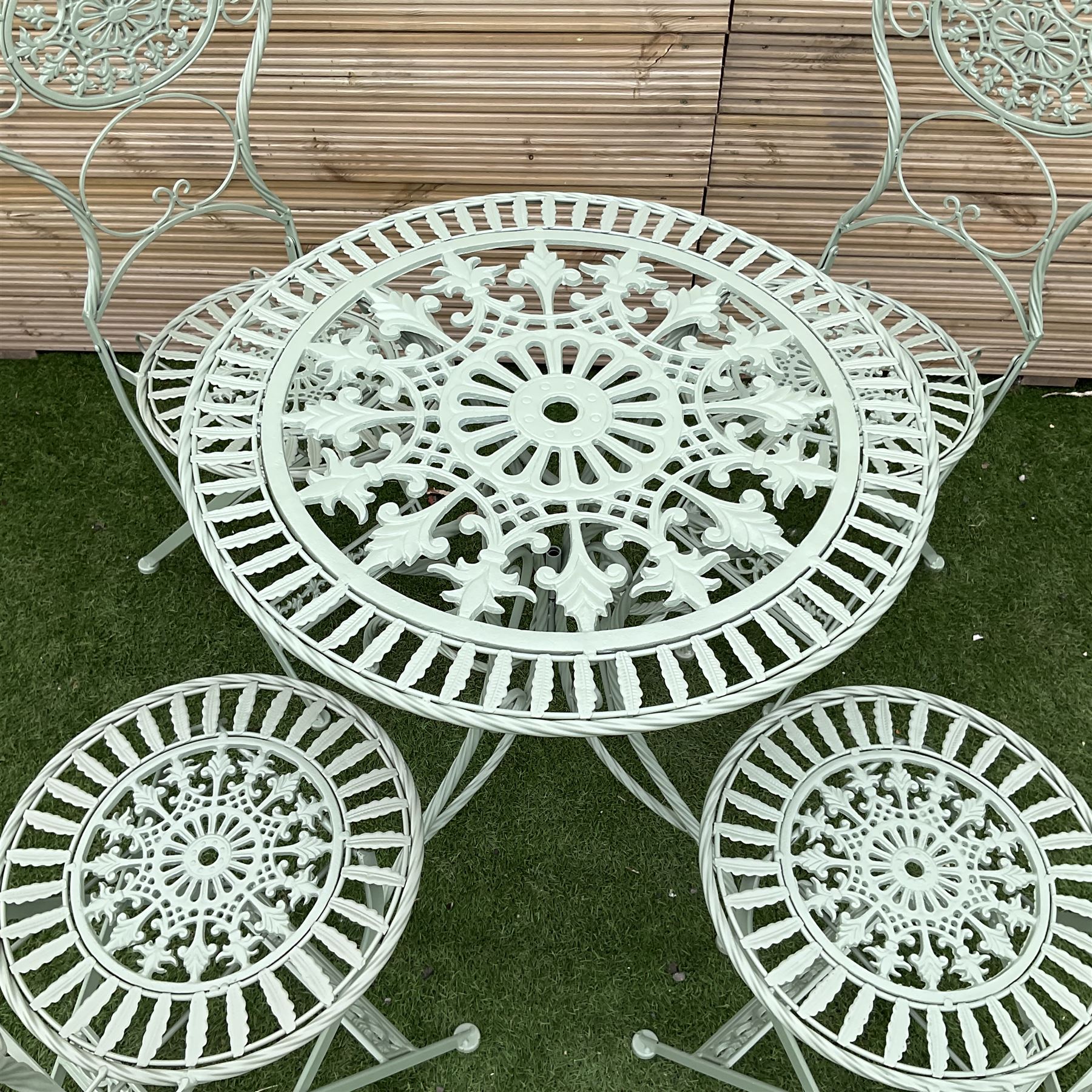 Circular wrought iron green painted garden table, and four folding