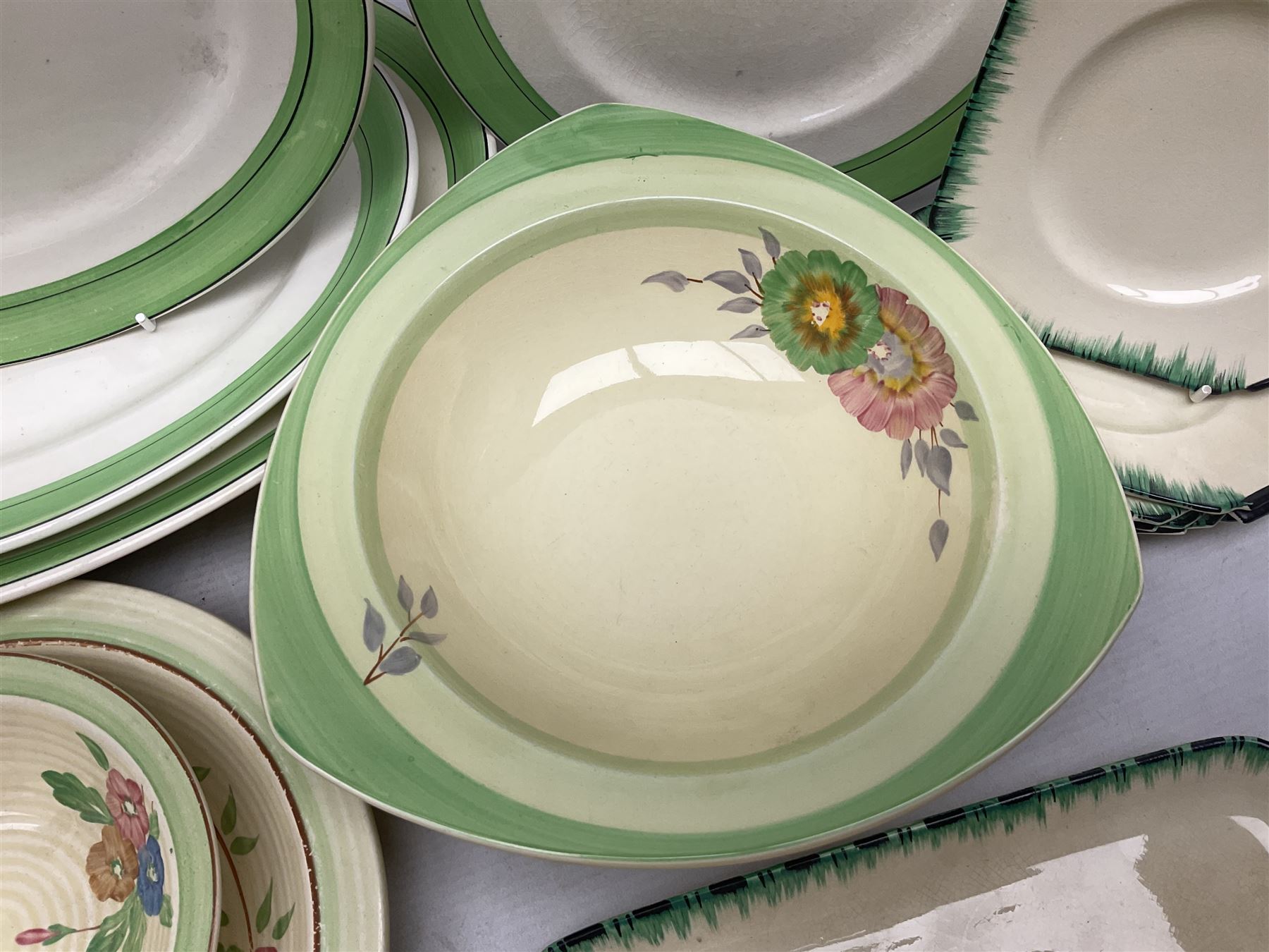 Clarice Cliff for Newport Pottery Corolla pattern tea and dinner wares, comprising triangular bowl, four side plates, two shallow bowls and teacup (a/f), together with a Clarice Cliff Wilkinson twin handled soup bowl and unassociated saucer both decorated with pink and yellow flowers, together with other mid century ceramics comprising Parrott and Company Coronet Ware, and Royal Staffordshire AJ. Wilkinson Ltd dinner wares