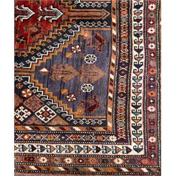 Southwestern Persian Qashqai hand-knotted carpet, the field with a lattice of hexagonal medallions in rust, indigo, and ochre, each containing stylised tree and floral motifs, flanked by lozenge panels with geometric designs, enclosed by multiple borders with rosettes and leaf motifs