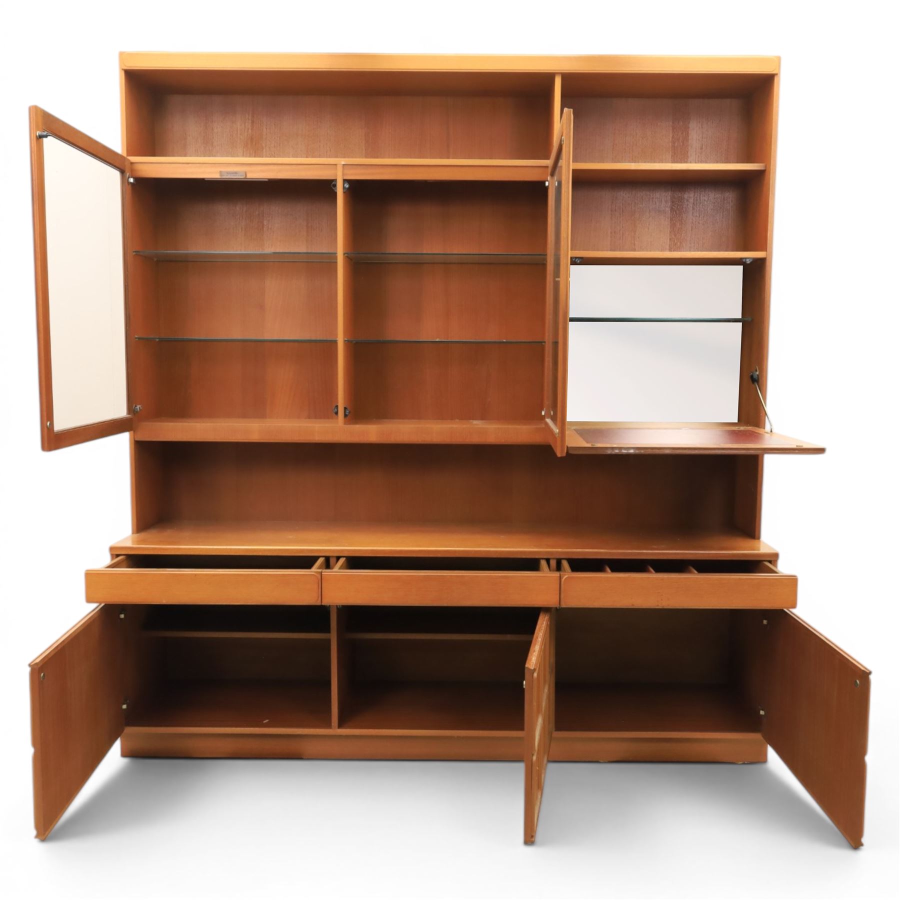 Mid-20th century teak wall display unit, featuring two glazed cupboards and fall front compartment with open shelves, above three drawers and cupboards to the base