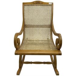 Late 20th century teak framed plantation style rocking chair, cresting rail carved with two elephants with upraised trunks, cane back and seat with scrolled arm terminals, rocker base united by turned stretcher