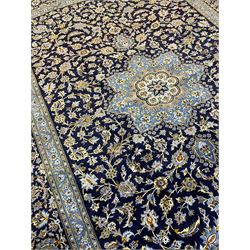 Central Persian Kashan indigo ground carpet, central lighter blue floral medallion surrounded by interlacing leafy branches and stylised plant motifs, the main border decorated with repeating floral motifs and scrolling branches, within guard stripes 