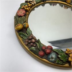 A 20th century circular framed mirror, the frame with painted fruit and flowers in relief, overall D34cm. 