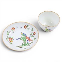 Chamberlain's Worcester teabowl and saucer, each of wrythen form decorated in the Sir Joshua Reynolds pattern, circa 1800, with long tailed Ho Ho bird perched upon green rockwork and surrounded by flowering vines, the saucer with iron red pattern number 203 beneath, teabowl H6cm D8.5cm, saucer D14cm