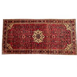 North West Persian Malayer Kelleh crimson ground rug, the central ivory medallion within a field decorated with all over Herati motifs, the guarder border with repeating stylised plant patterns and the adjacent bands with scrolling flower heads 