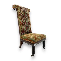 19th century mahogany framed prie-dieu chair, upholstered in red and green patterned fabric, high back with rolled top, standing on turned front supports with castors