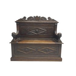 Late 19th century heavily carved oak monks bench, scroll carved pediment with central anthemion motif, panelled back with lozenge and carved green man mask, down swept arms in form of recumbent lions flanking hinged box seat, panelled base carved with masks and scrolls on moulded skirt