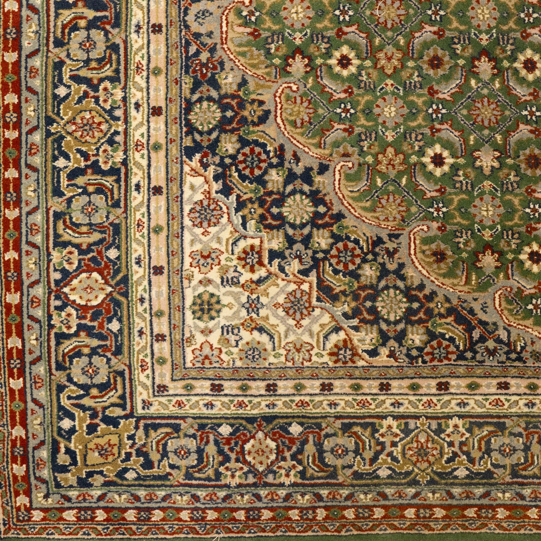 Central Persian Kashan rug, emerald green ground, with a central ivory, indigo, and brick red lobbed medallion with pendant finials, ivory spandrels, framed by multiple floral borders