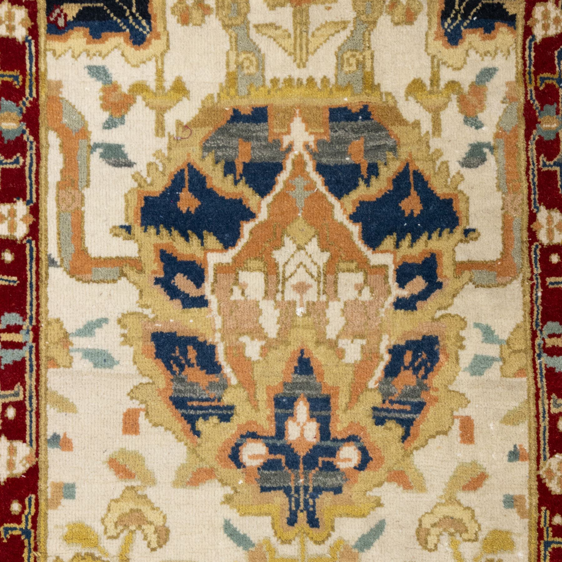 Agra wool runner, cream field decorated with large stylised palmettes, scrolling vines and flowerheads, enclosed by red main border with foliate motifs and fringed ends