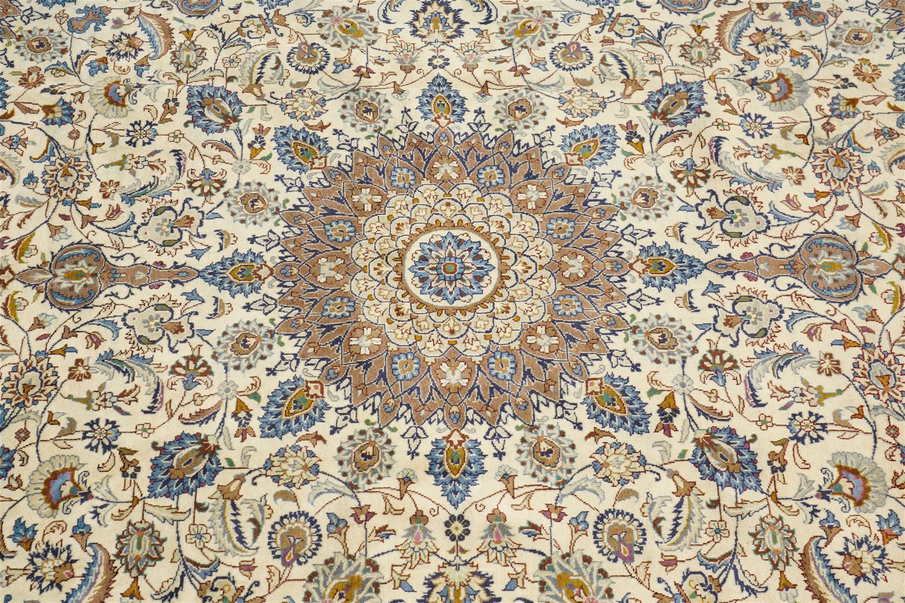 Central Persian Nain hand-knotted carpet, ivory field with central radiating medallion with pendants, issuing an all-over design of scrolling vines, palmettes, and floral sprays within confirming spandrels, framed a complimentary foliate border flanked by multiple guard stripes, with cotton fringe ends 