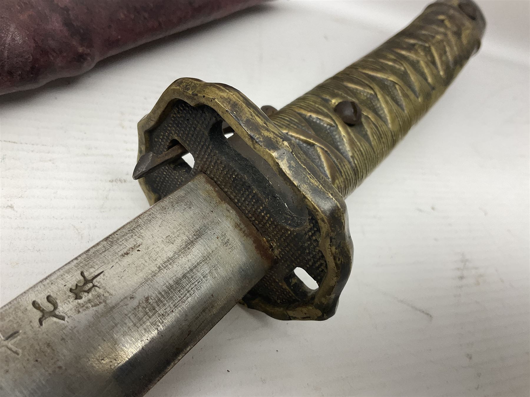 Copy of a WWII Japanese NCO sword, the 65cm slightly curving blade stamped with pseudo Japanese characters and cast brass simulated cord bound grip; in officer's leather bound field scabbard L97cm overall