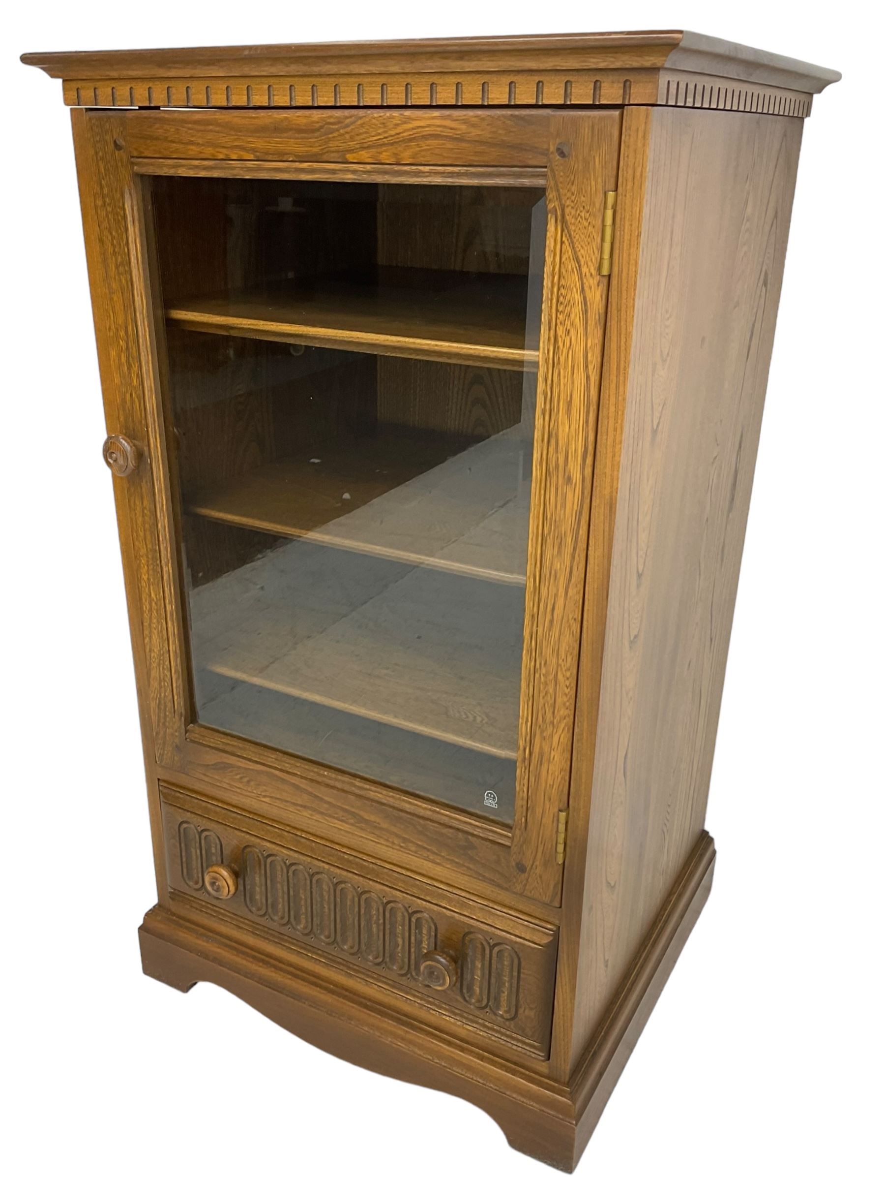 Ercol - mid-20th century dark elm 'Old Colonial' music cabinet, single glazed door enclosing three shelves, single drawer fitted to base