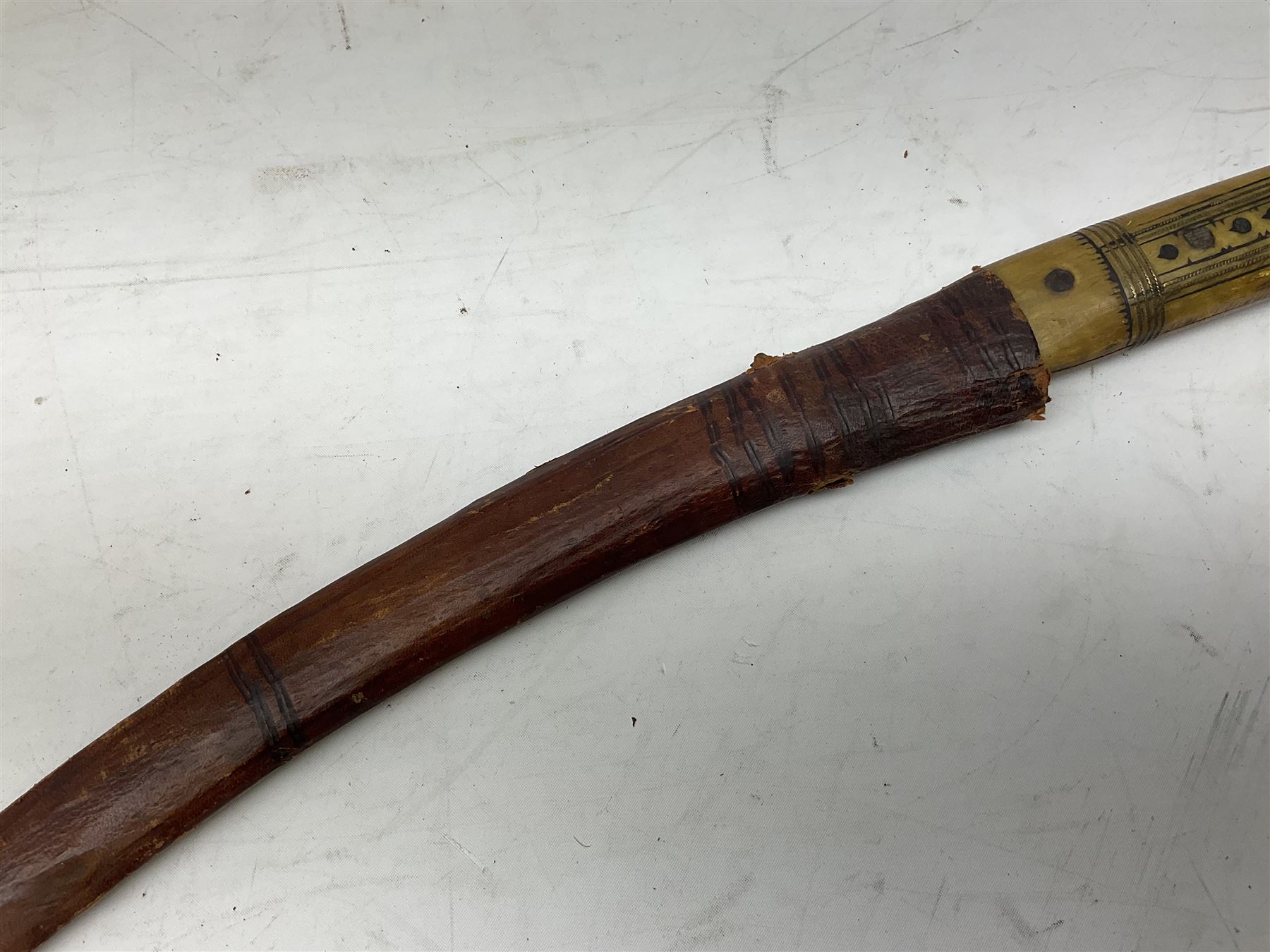 Near pair of African Moroccan Berber tribal Shula daggers each with engraved 39cm curving fullered steel blade, carved and inlaid horn grip and leather covered scabbard L57cm overall; kindjal style dagger with brass covered and jewelled grip and scabbard; another Eastern dagger with leather covered grip and scabbard; and a large Eastern knife with animal hide scabbard (5)